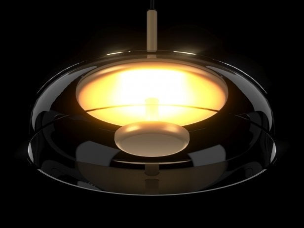 Modern pendant light with a black shade and gold interior on a dark background