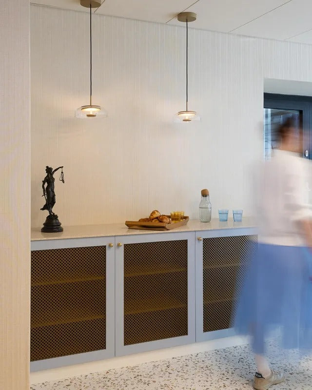 Modern interior with a cabinet, decorative items, and a person walking by.