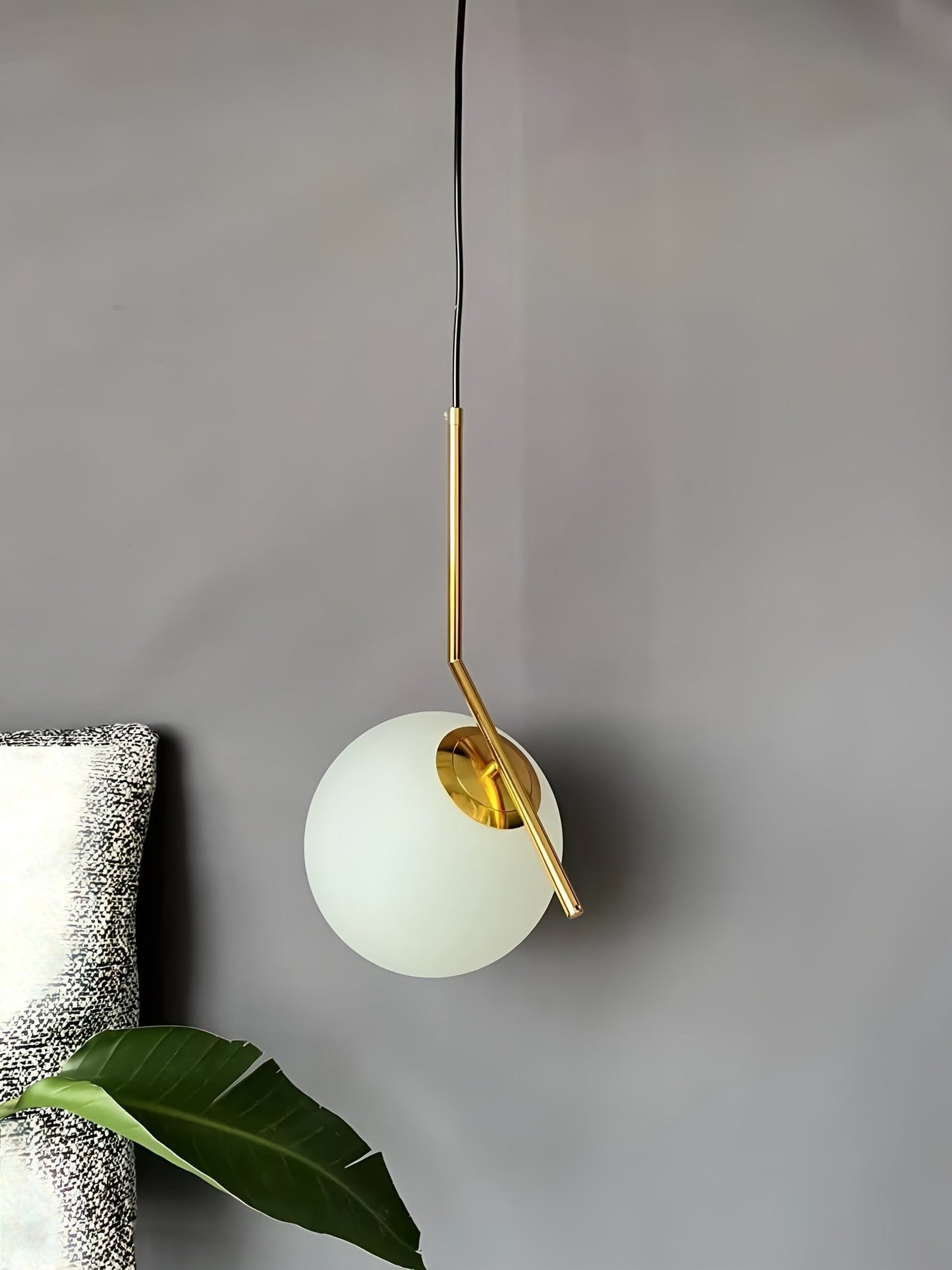Modern pendant light with gold fixture and white glass shade on a neutral background