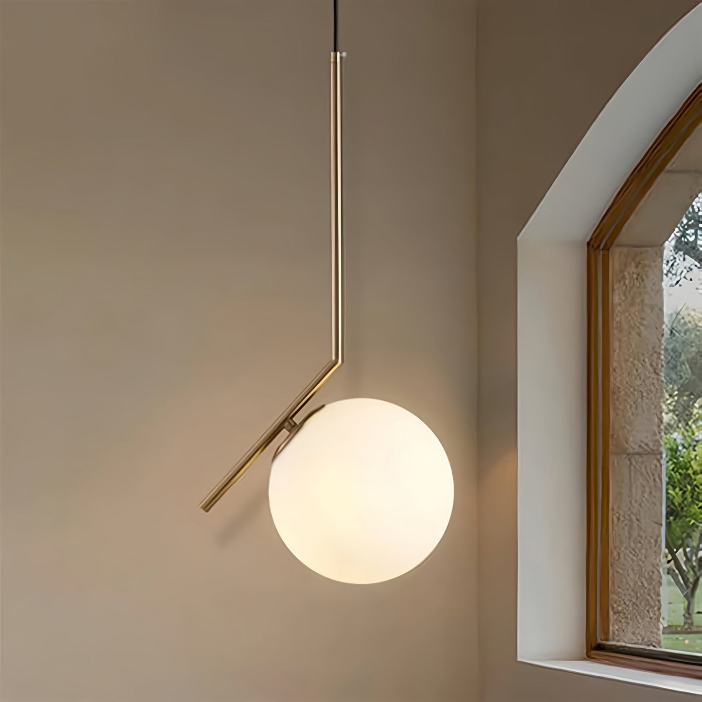 Modern pendant light with a spherical glass shade in a room with a window.