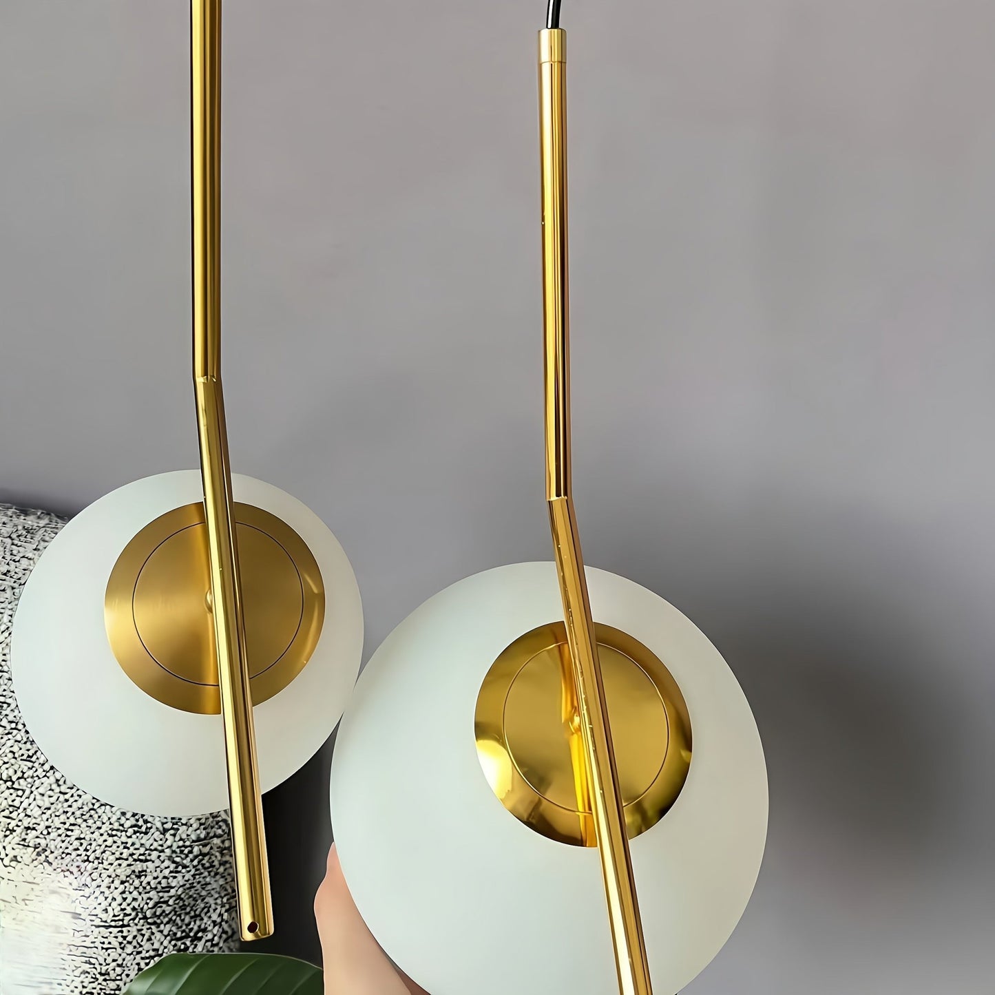 Two gold pendant lights with white shades on a gray background