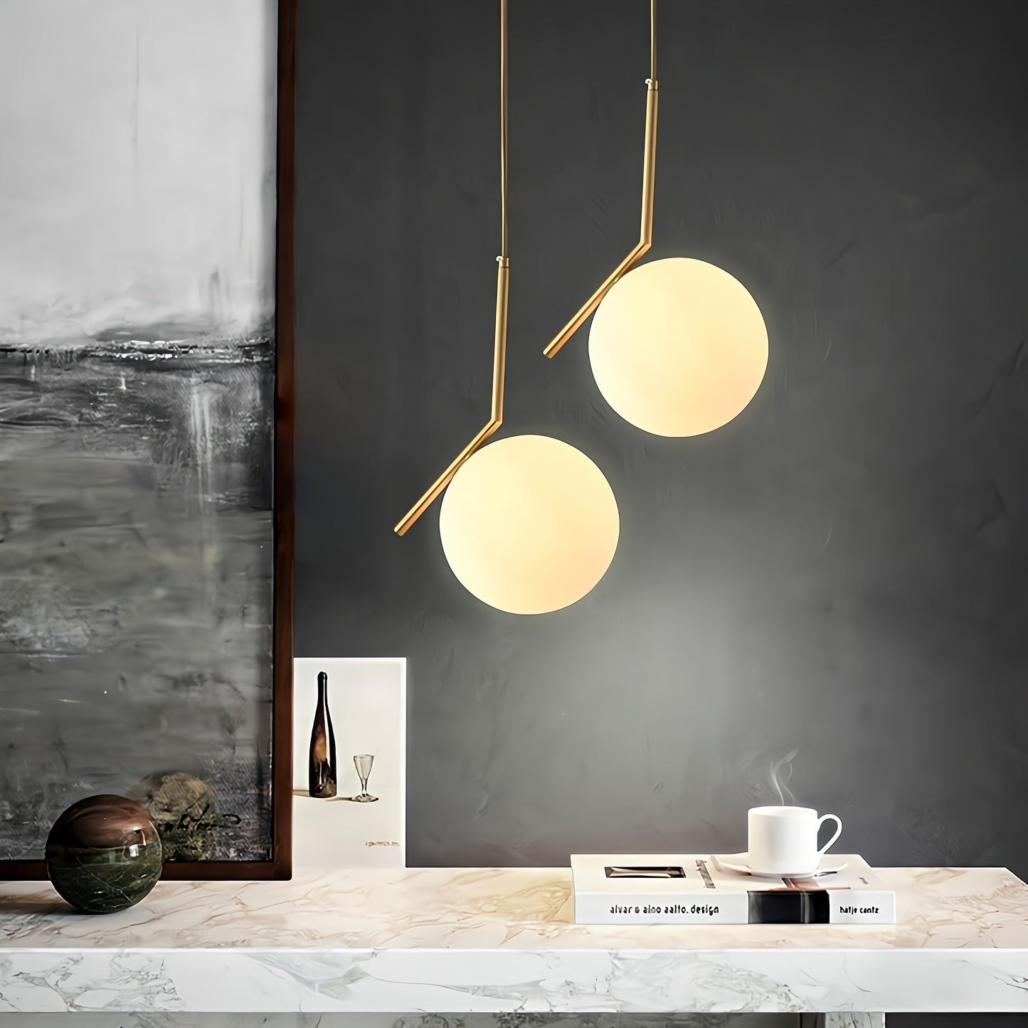 Modern pendant lights hanging above a table with decor items against a dark wall.