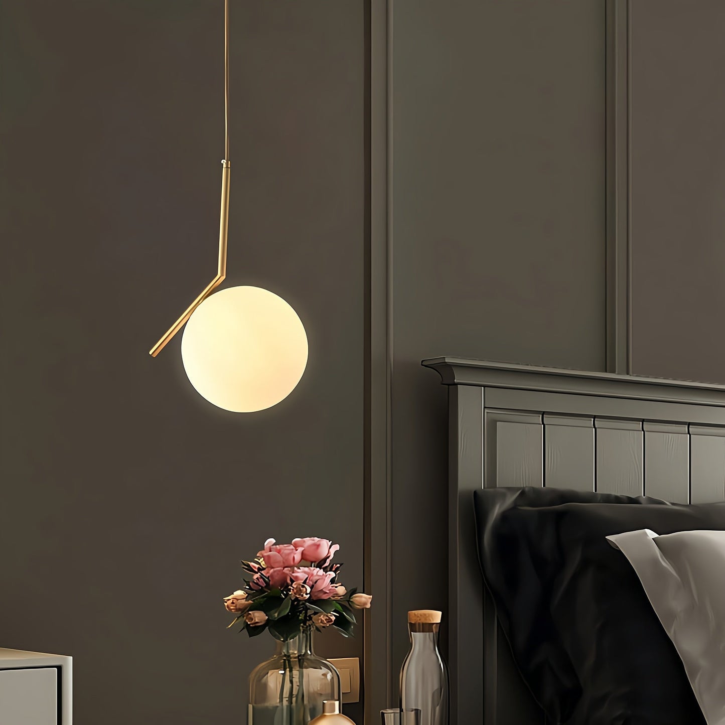 Modern pendant light hanging above a bed in a bedroom setting.
