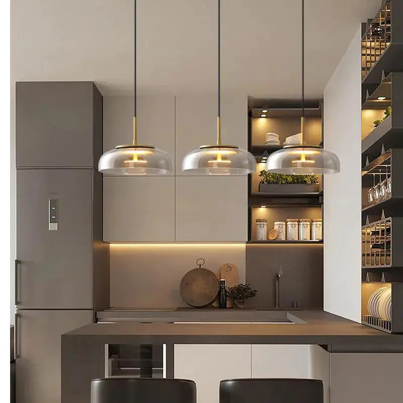 Modern kitchen interior with pendant lights, cabinets, and a refrigerator.