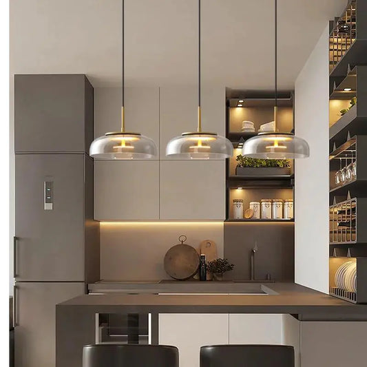 Modern kitchen interior with pendant lights, cabinets, and a refrigerator.