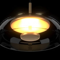 Modern pendant light with a black shade and gold interior on a dark background