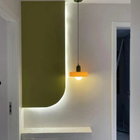 Modern interior design with a green wall, white shelf, and pendant light.