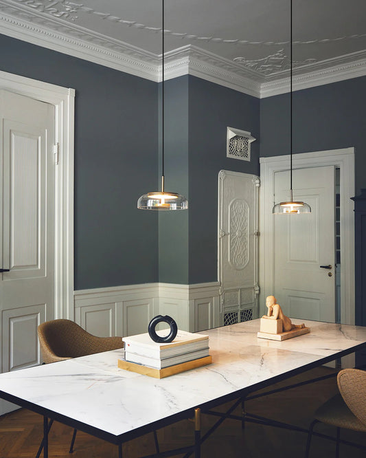 Modern interior with a marble table, chairs, and decorative items against a gray wall.