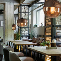 Modern restaurant interior with wooden tables, chairs, and pendant lights.