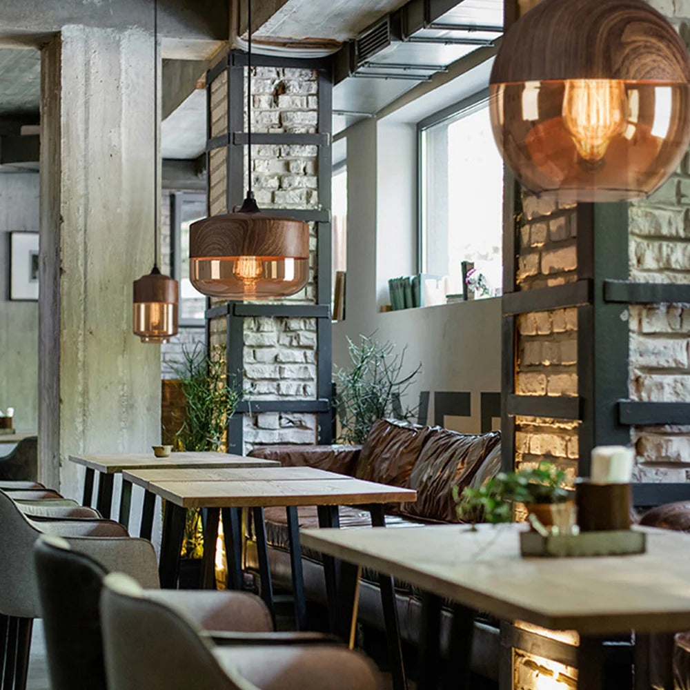 Modern restaurant interior with wooden tables, chairs, and pendant lights.