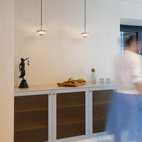 Modern interior with a cabinet, decorative items, and a person walking by.