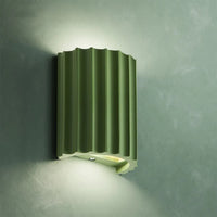 Green wall-mounted light fixture on a textured gray wall