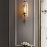 Wall-mounted lamp with a decorative glass shade on a gray wall.