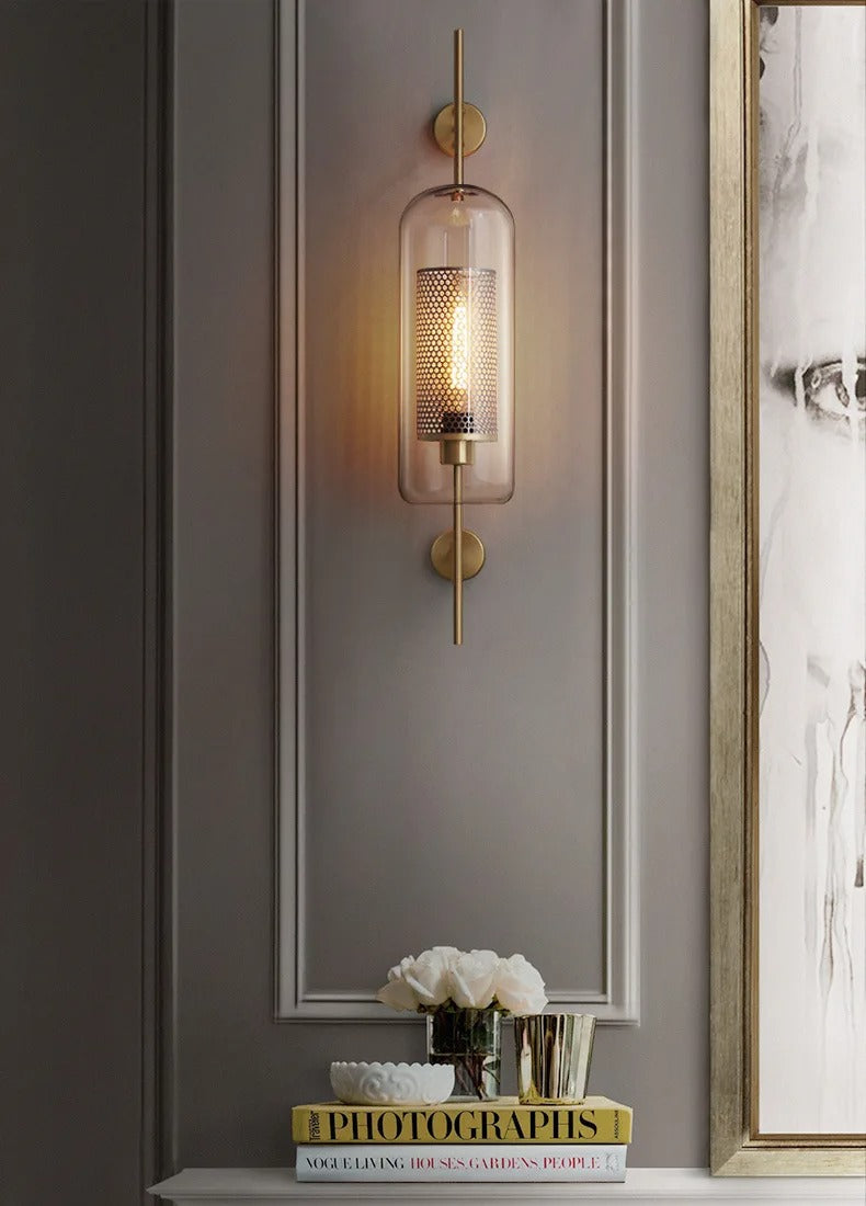 Wall-mounted lamp with a decorative glass shade on a gray wall.
