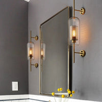 Bathroom with a mirror, gold fixtures, and wall lights on a gray wall.