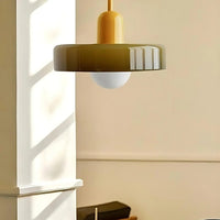 Modern pendant light with a gold fixture and greenish-brown shade hanging in a room.