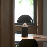 Black geometric lamp on a desk with a window in the background