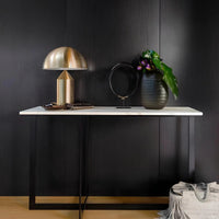 Modern interior with a black cabinet, gold lamp, and decorative items against a dark wall.
