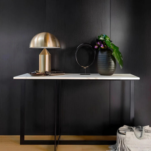 Modern interior with a black cabinet, gold lamp, and decorative items against a dark wall.