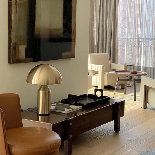 Modern living room with a gold table lamp, wooden coffee table, and beige armchair.