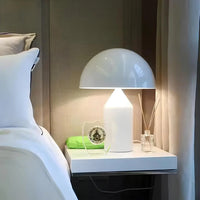 White table lamp on a nightstand next to a bed with pillows