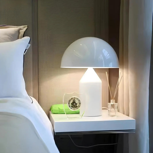 White table lamp on a nightstand next to a bed with pillows