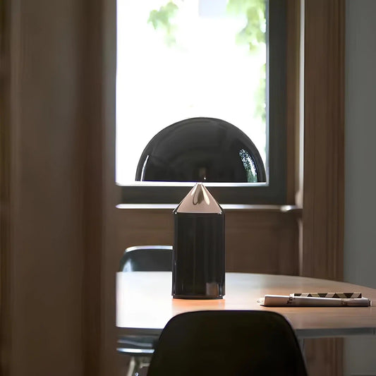 Black geometric lamp on a desk with a window in the background