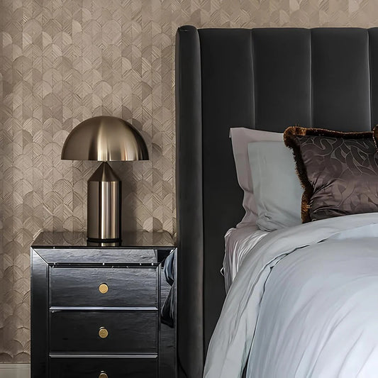 Bedroom with dark upholstered headboard, nightstand with lamp, and patterned wallpaper.