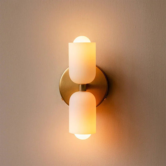 Wall-mounted light fixture with two glass shades on a beige wall.