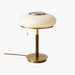 Table lamp with a white shade, gold base, and brown stem on a white background