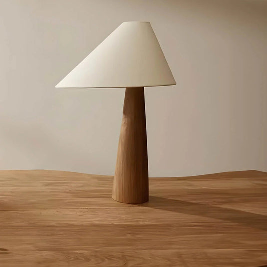 Table lamp with wooden base and white shade on a wooden surface