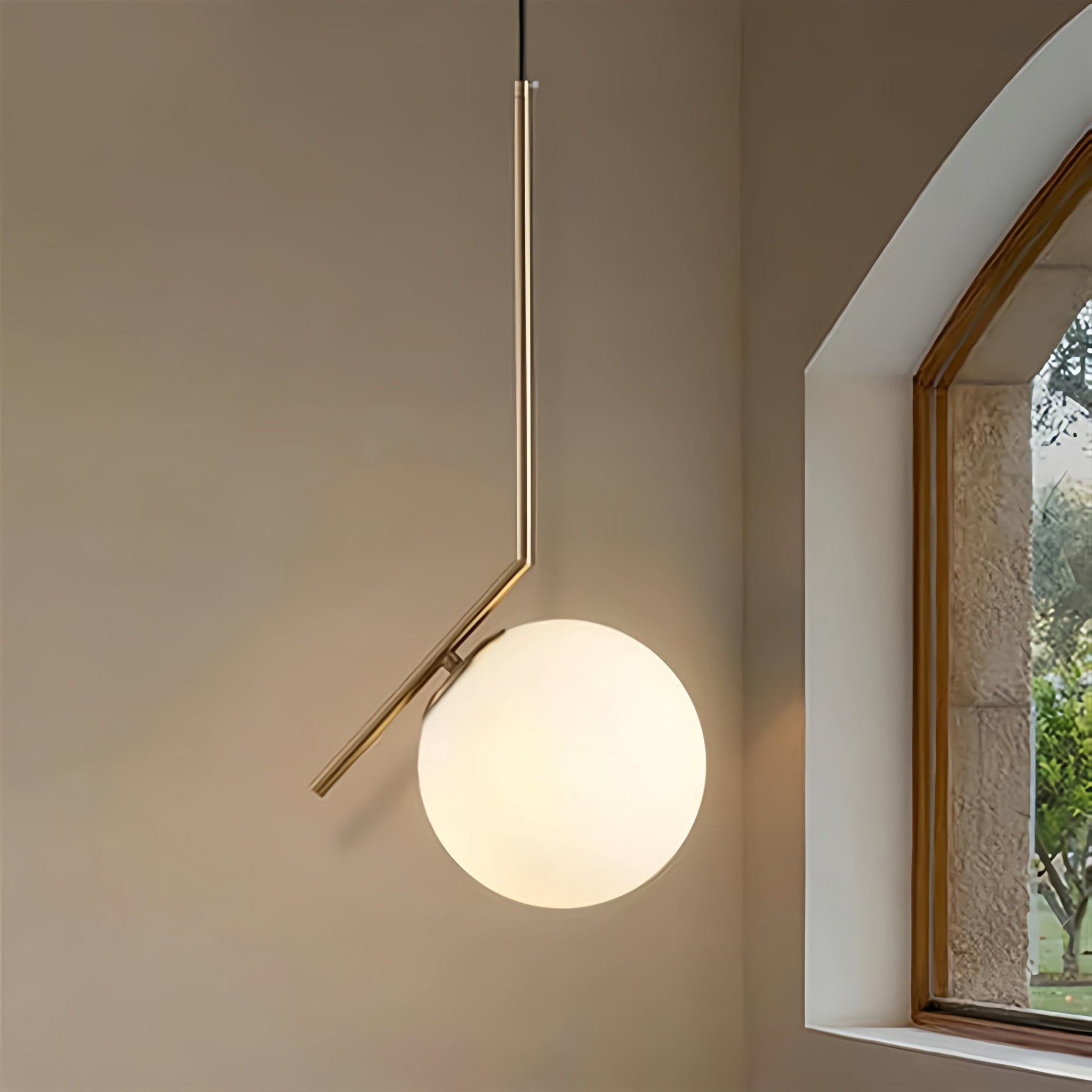 Modern pendant light with a spherical glass shade in a room with a window.