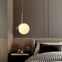 Modern bedroom with a hanging pendant light, bed, and decorative items.