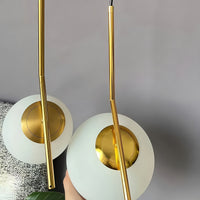 Two gold pendant lights with white shades on a gray background