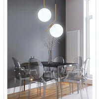 Modern dining room with black table and transparent chairs, featuring two pendant lights.
