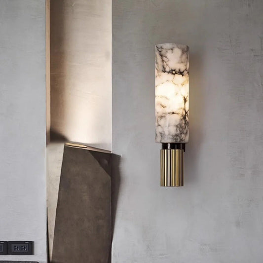 Wall-mounted lamp with marble-like shade and gold base on a gray wall.